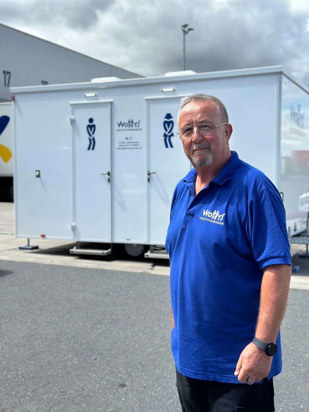 Der Inhaber von Wollys vor zwei Toilettenwagen